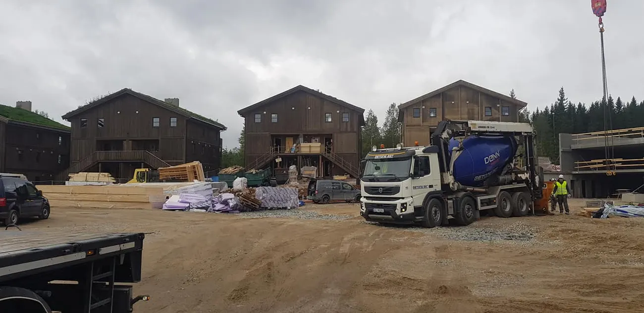 Boligblokker i tre under oppføring, med en betongbil inne på byggeplassen